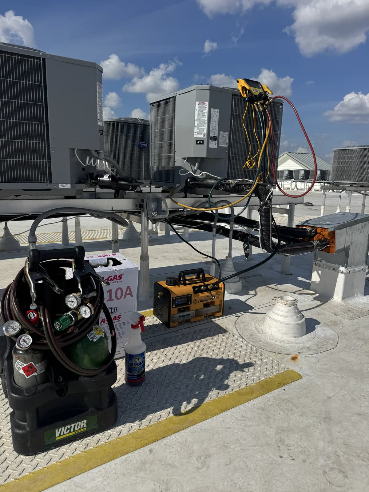 Rooftop HVAC service setup with recovery tank, vacuum pump, and service tools